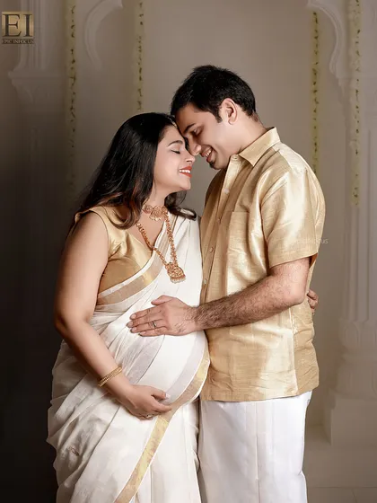 Celebrating heritage and love. This couple's portrait, featuring a traditional white and gold Kerala saree, beautifully blends cultural elegance with the intimacy of the maternity journey in a classic studio setting.