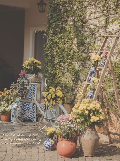 A whimsical photo corner with a rustic garden feel. We styled this nook with a vintage bicycle, a wooden ladder, and an abundance of flowers in terracotta pots and patterned vases.