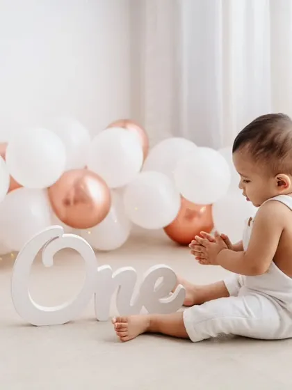 A quiet, contemplative moment from a first birthday shoot. The simple setup with white and rose gold balloons creates a soft and elegant look.