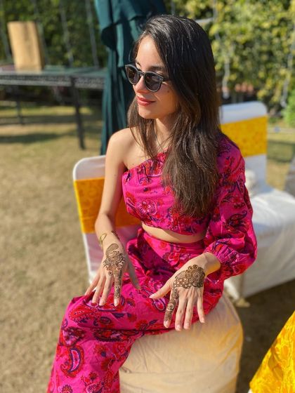A client looking radiant in a pink outfit, with her simple and modern mehndi designs. This is a perfect look for a daytime wedding event.