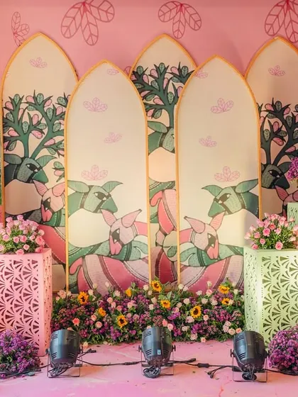 This decor for a carnival-themed event features custom-printed panels with artistic illustrations of peacocks and trees. Paired with colorful floral arrangements, it creates a unique and culturally rich backdrop.