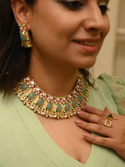 A client trying on a stunning green and pink necklace set. This close-up shows the intricate craftsmanship and beautiful color combination, perfect for adding a regal touch to a festive outfit.