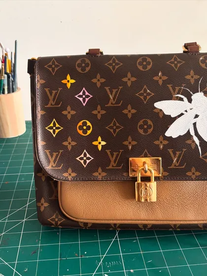 The "before" shot of a Louis Vuitton bag, with the base sketch of a bee and some colorful monogram ideas laid out. This is where the transformation begins.