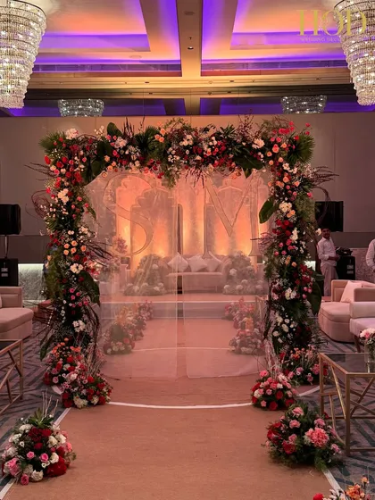 A breathtaking floral archway leading to the main stage, with the couple's initials subtly integrated into a sheer curtain, creating a personal and romantic entrance.