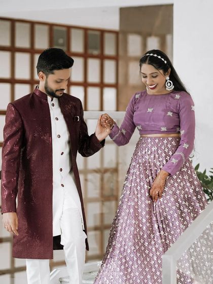 The couple sharing a loving moment on the stairs, the groom leading his bride, both dressed in stunning reception attire.