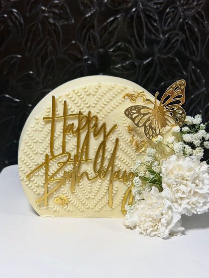 An elegant "Happy Birthday" cake with a textured buttercream finish, a golden butterfly, and delicate fresh flowers. Simple, yet so beautiful.