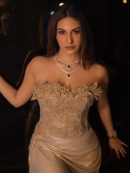A close-up of Amyra Dastur against a dark, reflective surface. The soft lights in the background create a beautiful, glowing effect.