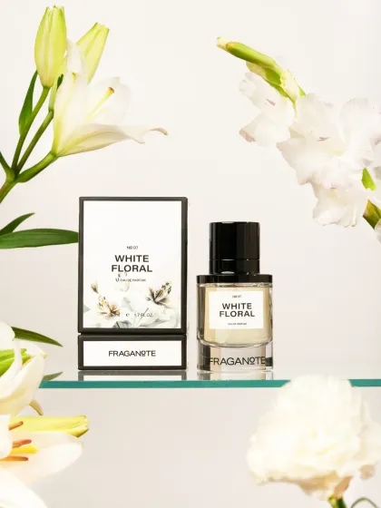 An elegant shot of 'White Floral' perfume, framed by fresh white lilies. Using real flowers as props enhances the story of a floral fragrance.