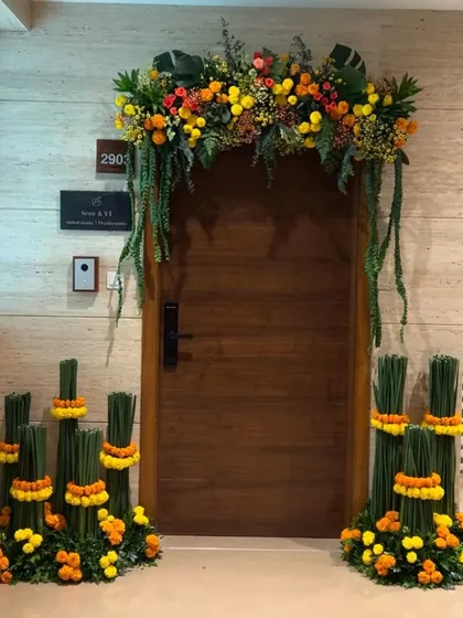 To create a warm and festive welcome, we designed this entrance decor using vibrant marigolds and lush greenery. The arrangement frames the doorway, with unique vertical floral stands on either side adding a modern touch to a traditional element.