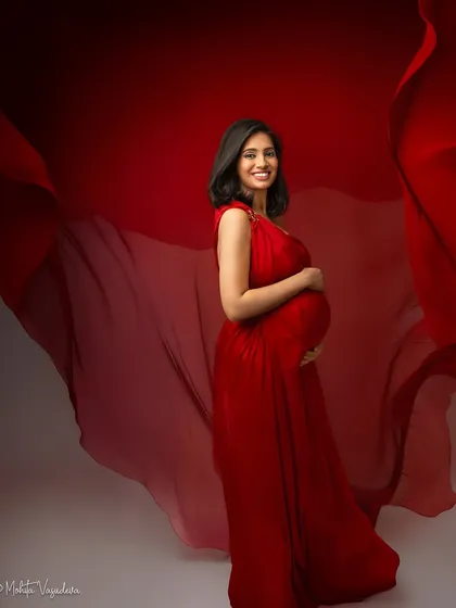 A radiant smile against a backdrop of flowing red fabric. This portrait is pure joy and confidence.
