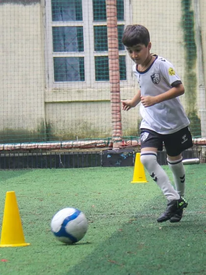 This player shows great running form while dribbling, combining athleticism with technical skill during a training exercise.
