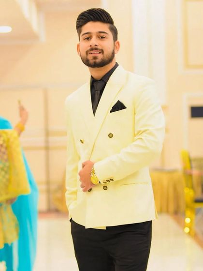 A stylish party look featuring a double breasted white blazer. The grooming is clean and modern, with perfectly coiffed hair and a well-defined beard, making him stand out at any celebration.