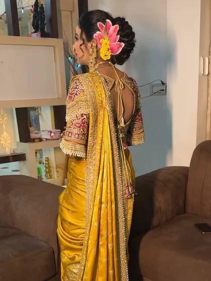 The back view of the yellow Nauvari, showing the intricate hairstyle and blouse details.