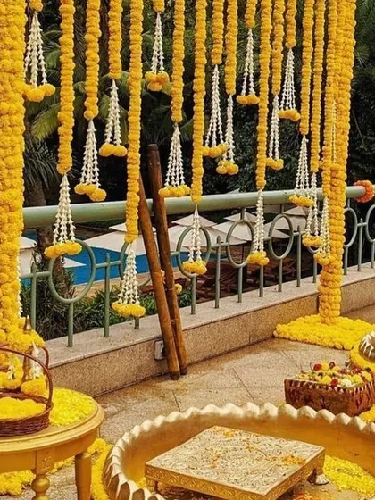 A traditional Haldi setup with a backdrop of yellow marigold curtains, creating a vibrant and auspicious setting for the ceremony.