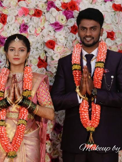 A lovely couple posing after their wedding ceremony. The bride's soft pink saree and subtle makeup are perfectly coordinated with the groom's formal suit.