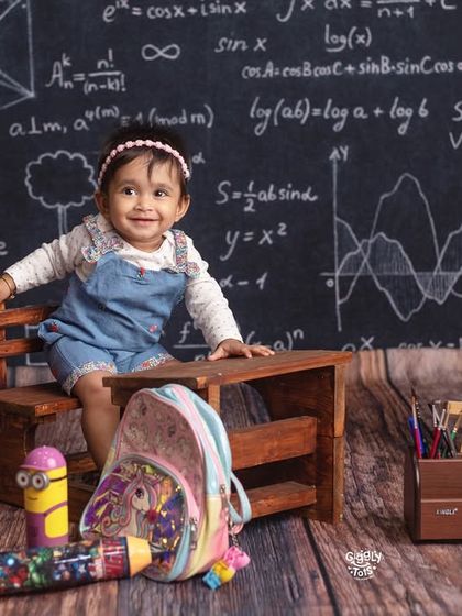 Welcome to class! This adorable little student is ready to learn, sitting at her desk in front of a chalkboard full of equations.