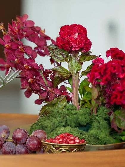 A detailed centerpiece from the 'दाड़म ka Bageecha' event. We combined deep red orchids and celosia with fresh grapes and pomegranate seeds in a brass bowl, creating a rich, multi-sensory experience.