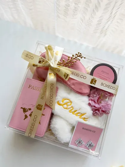 A slightly different angle of the acrylic bride-to-be hamper, showing the arrangement of the passport cover, slippers, and other items.
