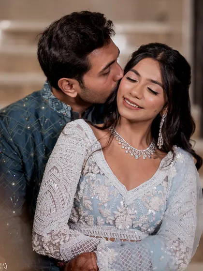 An intimate close-up of the groom kissing the bride's cheek. This shot captures a moment of pure affection and happiness, highlighting their connection and the bride's beautiful makeup and jewelry.