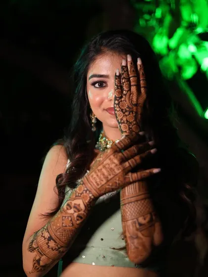 A stunning shot of a bride peeking through her mehandi-adorned hands. A classic and beautiful pose for any bride-to-be.