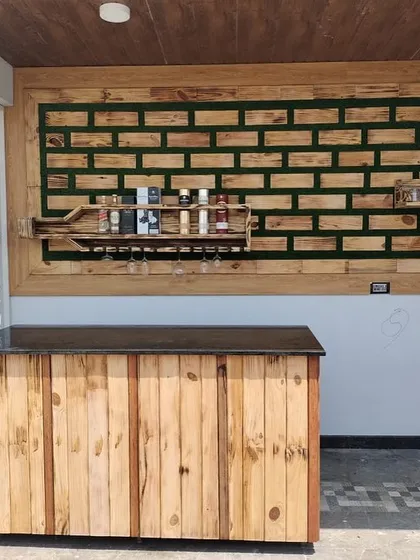 Here you can see the complete custom bar installation in its space. The bottle-shaped wall art is paired with a matching rustic wood bar counter, creating a fully functional and cohesive entertainment area for a home or terrace.