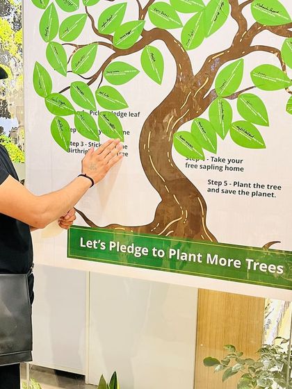 A smiling participant adds his pledge leaf to our tree. Each leaf represents a personal commitment to our shared goal of a healthier planet.