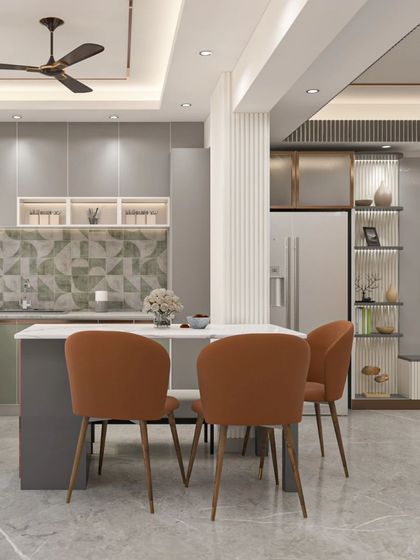 An open-plan kitchen and dining area from our Bhagalpur project. The design features sage green and grey cabinets, a patterned tile backsplash, and a functional island that doubles as a dining table.