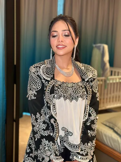 A serene moment. The soft lighting highlights the beautiful details of her makeup and the intricate embroidery of her jacket.