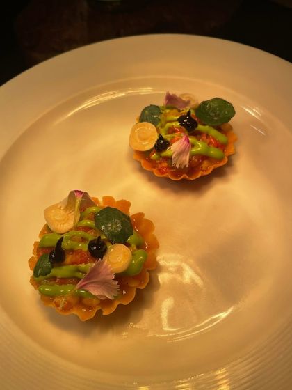 A pair of delicate tartlets, filled with a savory cream and garnished with colorful sauces and edible flowers. A perfect amuse-bouche.