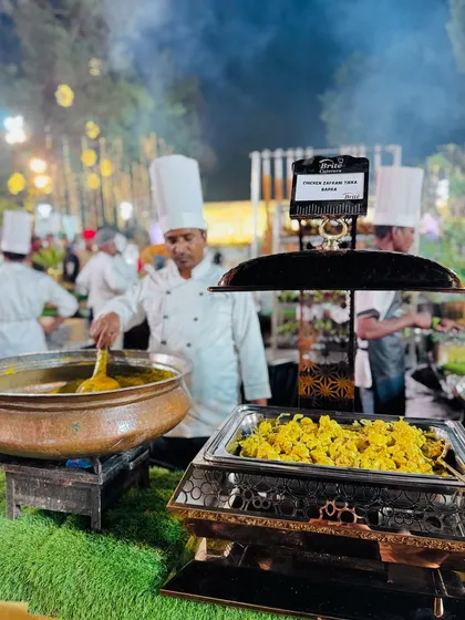My chef stirs a large pot of Chicken Zafrani Tikka Barra, ensuring the flavors are perfectly blended.