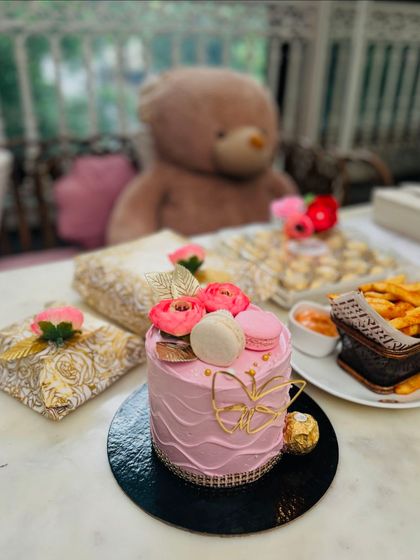 A chic pink cake with a modern gold design, pictured here in a beautiful cafe setting. Perfect for a stylish birthday brunch.