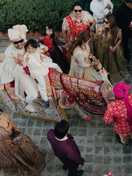An aerial view capturing the groom's vibrant baraat procession, featuring a unique magic carpet entrance.