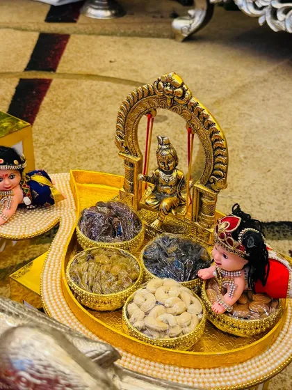 Every detail matters to me. This dry fruit platter for a naming ceremony was designed around a beautiful miniature of Lord Krishna on a swing, surrounded by small bowls of cashews and raisins, creating a divine and memorable gift.