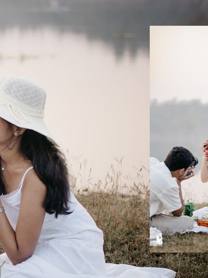 A playful moment during a lakeside picnic shoot, where the groom-to-be takes a photo of his smiling fiancée.