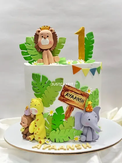 A cute jungle theme cake for a first birthday, with a friendly lion, giraffe, and elephant. All the animal figures are handmade and edible.