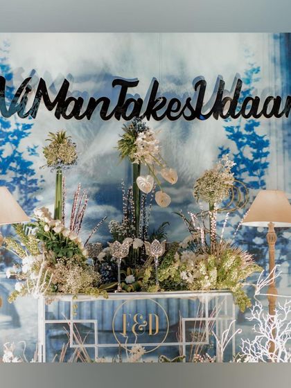 A custom bar or photo-op area for the winter-themed wedding. The backdrop features a blue and white print, with the couple's hashtag and elegant floral arrangements.