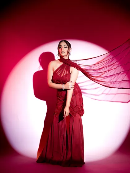 A full-length shot where the flowing red gown creates a dramatic backdrop for the glittering diamond jewelry. The styling uses a classic spotlight effect to create a sense of red-carpet glamour and highlight the accessories.