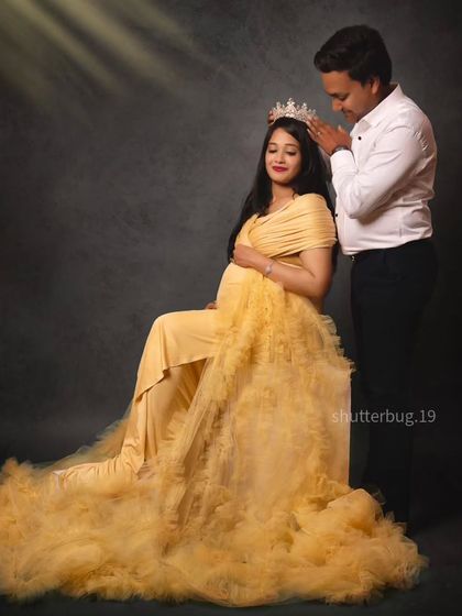 A sweet, interactive pose where the father-to-be places a crown on the head of the mom-to-be. It's a beautiful way to symbolize her role as the queen of their growing family.