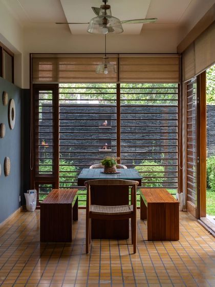 The dining area is surrounded by louvered windows, allowing diners to feel connected to the garden while being sheltered from the elements.