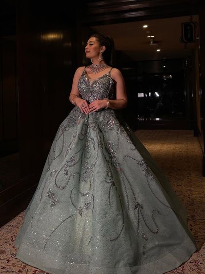 A client looking radiant in a mint shimmer organza flared gown. The dress is encrusted with sequins and crystals, creating a dazzling effect.