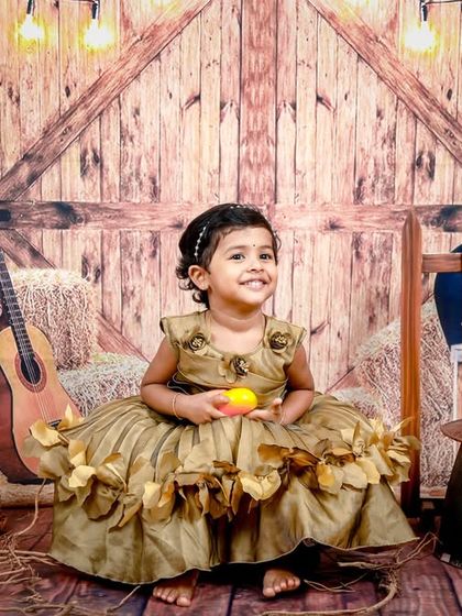 Yee-haw! A rustic barnyard theme for a little cowgirl. With a wooden backdrop, hay, a guitar, and a saddle, this studio setup is full of country charm.