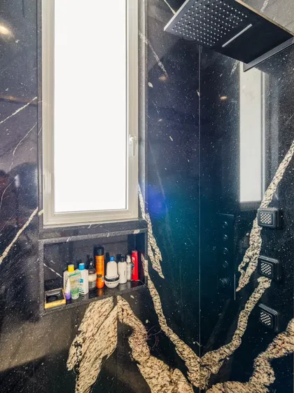 A detail shot of the spa-like shower, featuring a rainfall showerhead and rejuvenating body jets. This is where luxury and relaxation meet.