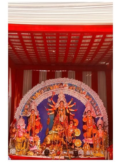 A Durga idol housed within a pandal structure with a striking red and white striped ceiling.