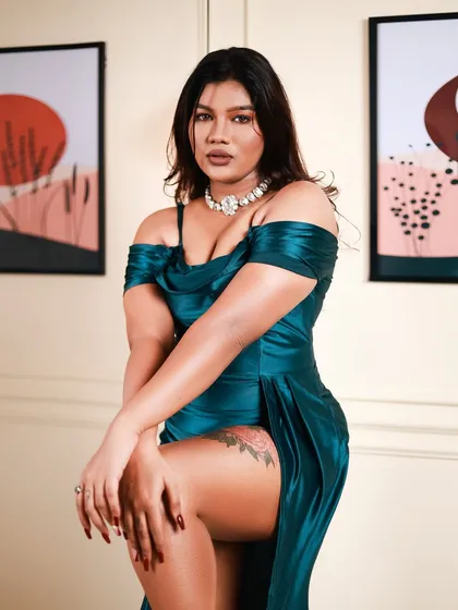 This is a powerful, glamorous portrait. The pose, with the high-slit teal satin dress, is confident and strong, and the studio lighting perfectly highlights the texture of the fabric.