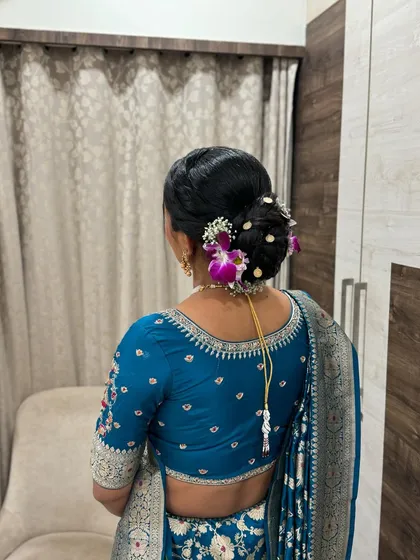 An elegant bridal bun, adorned with fresh purple and white orchids. This classic hairstyle is perfect for a sophisticated wedding or reception look.