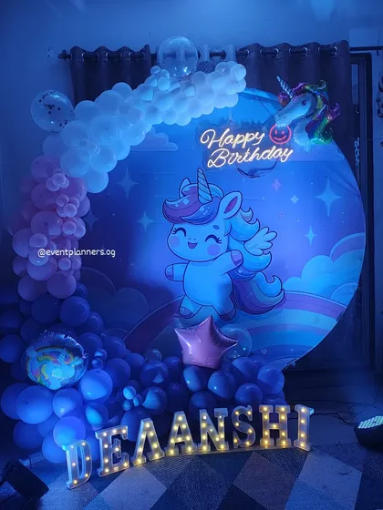 A magical unicorn-themed birthday setup with a cloud-like balloon effect and a large character backdrop.