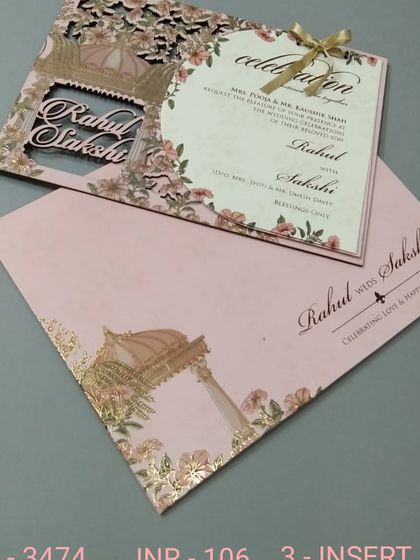 This invitation features a delicate laser-cut floral pattern on a pink cover. The main insert is shaped and tied with a ribbon, adding to its charm.