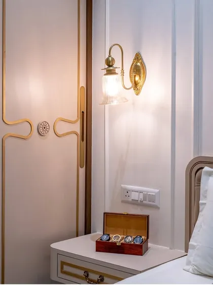 A detail shot of the vintage-style brass wall sconce and the custom wardrobe handle, showcasing our attention to period-appropriate hardware and lighting.