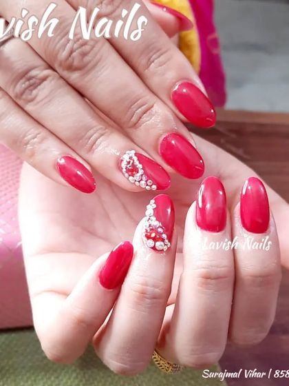 A vibrant red nail set with accent nails featuring a beautiful pattern made of tiny pearls and rhinestones.