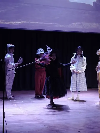The full cast of 'The Wizard of Oz' confronts the Wicked Witch. This is a powerful ensemble moment that showcases dramatic tension and collaborative storytelling.